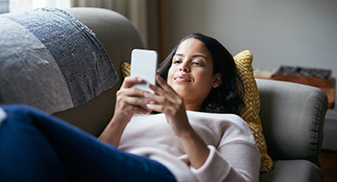 Woman looking at phone screen while resting on couch